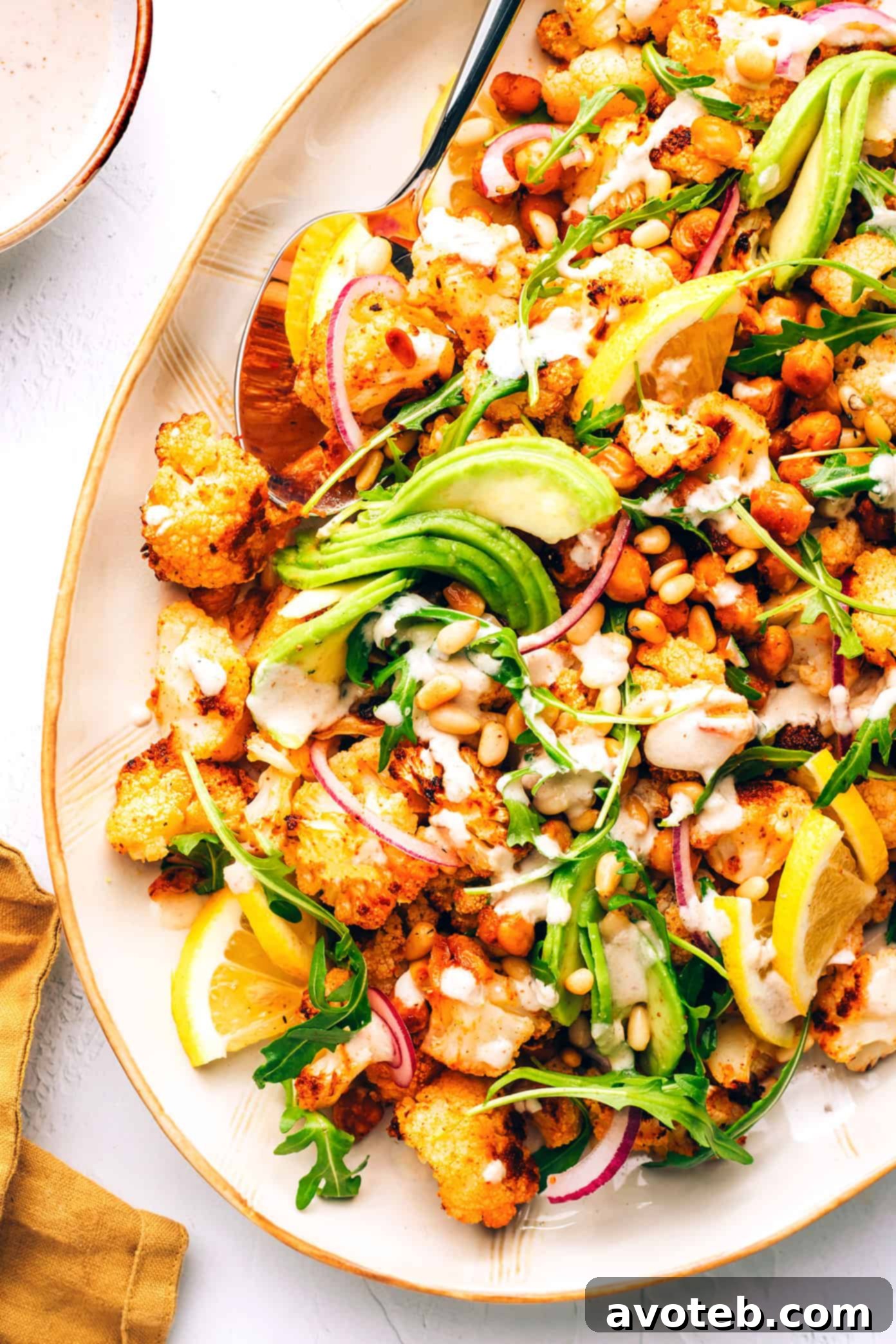 A beautifully presented bowl of Roasted Cauliflower, Chickpea, and Arugula Salad on a wooden table, ready to be enjoyed.