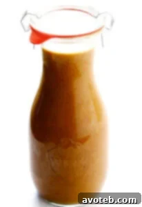 A vibrant, creamy Thai Peanut Dressing in a glass jar, perfect for drizzling over salads or as a dip.