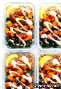 A vibrant roasted sweet potato, chickpea, and kale salad bowl with a creamy tahini dressing, garnished with fresh herbs and lemon wedges.
