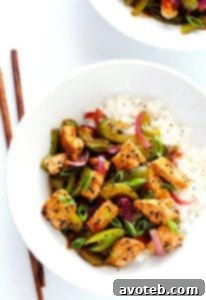 A vibrant plate of Black Pepper Chicken stir-fry, with tender chicken pieces, crisp bell peppers, celery, and red onion, coated in a dark, glossy black pepper sauce.