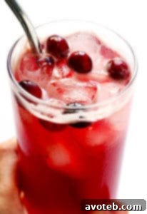 Cranberry Bourbon Fizz cocktail in a glass with cranberries and a rosemary sprig