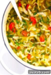 A bowl of Herb-Loaded Chicken Noodle Soup, garnished with fresh herbs and black pepper.