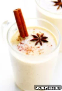 A glass of Chai Eggnog garnished with star anise and cinnamon sticks.