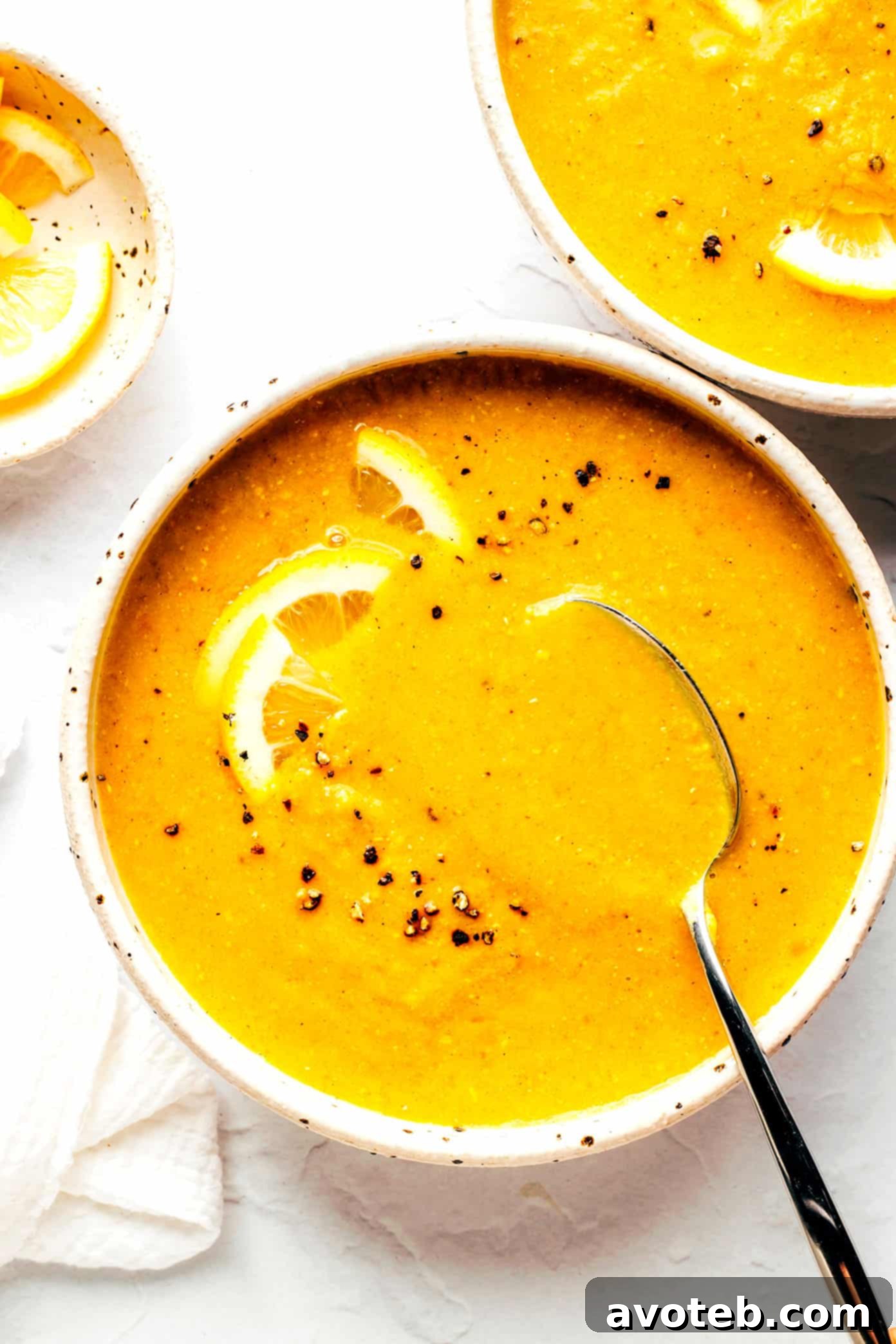 Lemony Red Lentil Soup served in two beautiful bowls, garnished with fresh herbs and lemon slices.