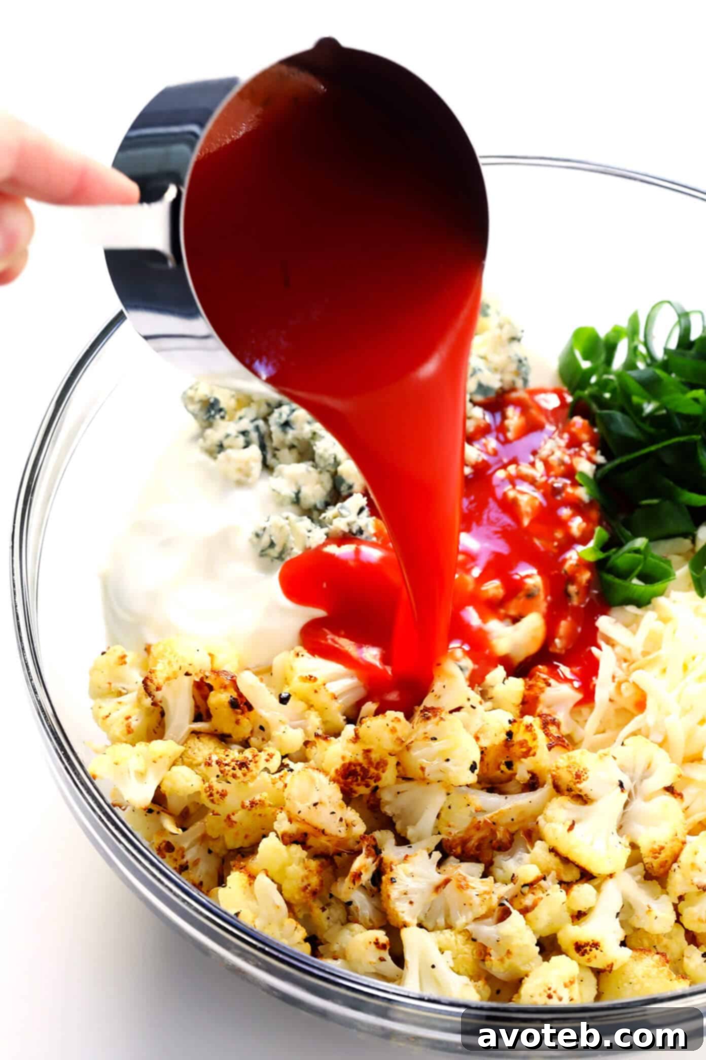 Mixing roasted cauliflower with creamy ingredients and hot sauce for the Buffalo Cauliflower Dip.