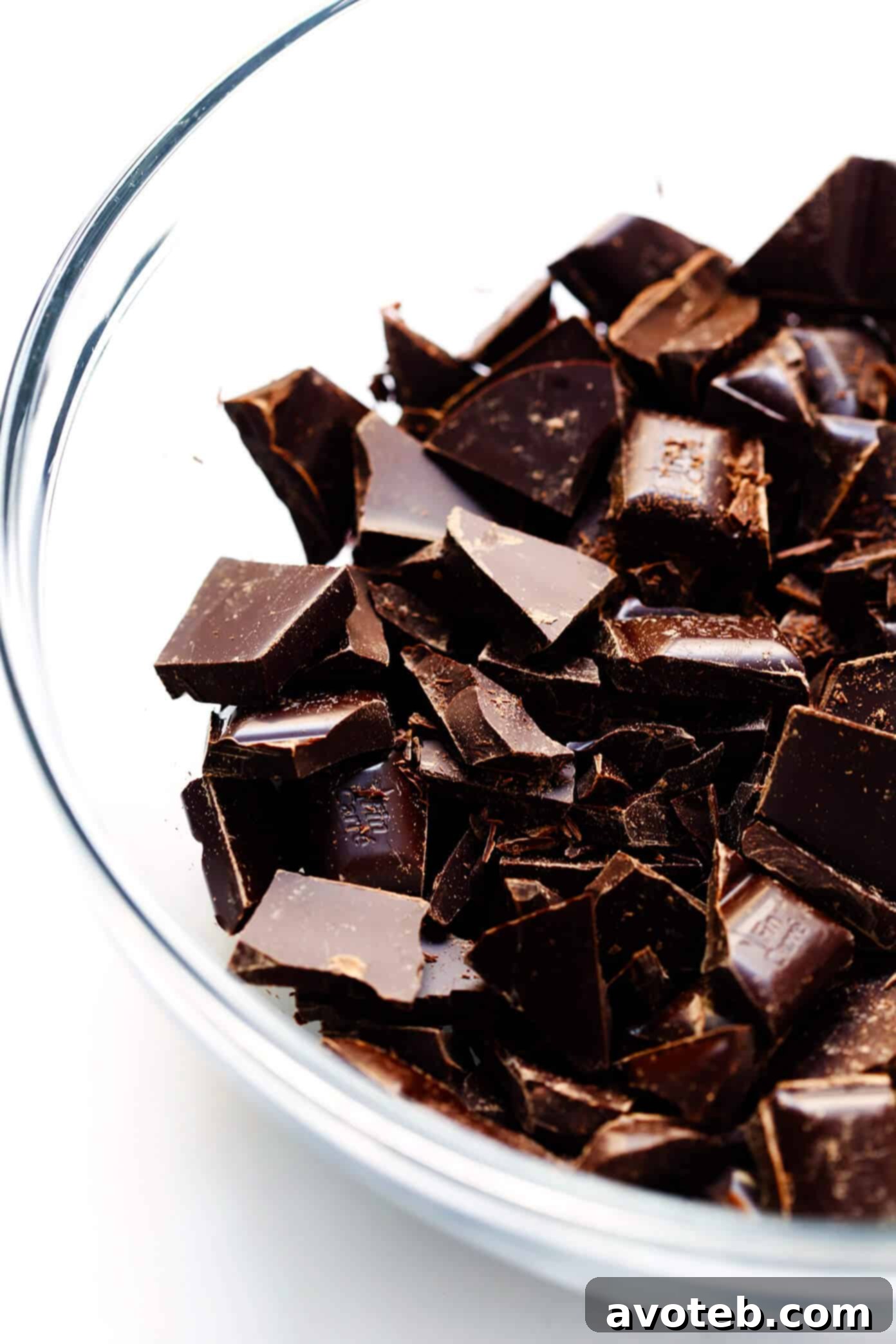 Roughly chopped premium dark chocolate bars arranged on a wooden cutting board, ready for melting.