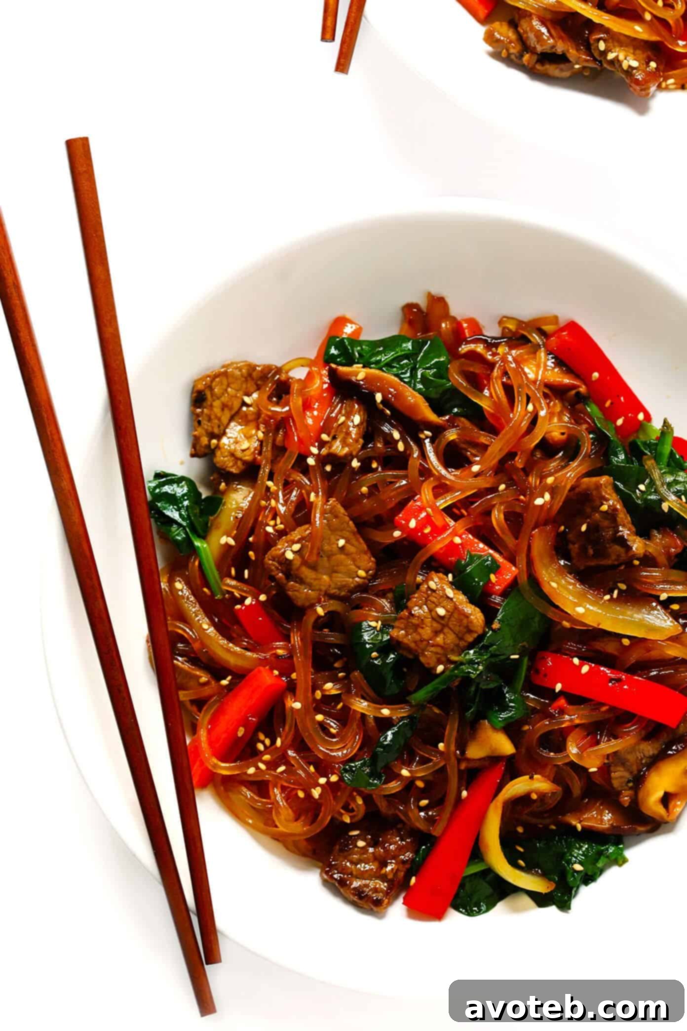 This Japchae (Korean noodle stir-fry) recipe is easy to make in just 30 minutes. It can be customized with your choice of veggies and protein (beef, chicken, shrimp, or tofu). And it is SO delicious! | gimmesomeoven.com #korean #noodle #stirfry #saute #pasta #beef #glutenfree #vegetarian #vegan #asian #dinner #mealprep #healthy Japchae with beef and vibrant vegetables, ready to serve