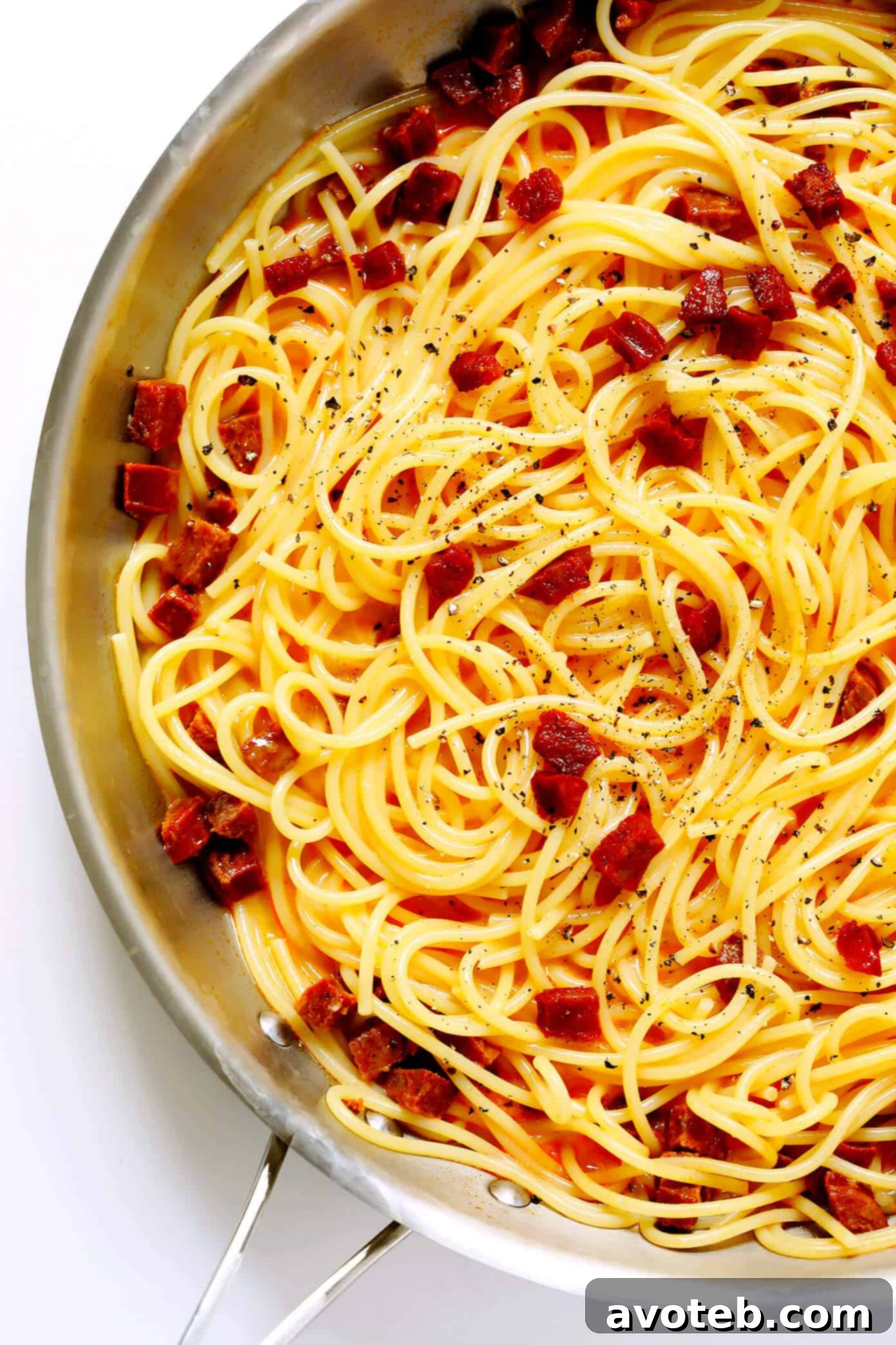 Tossing Spaghetti Carbonara with Spanish chorizo. Spanish Chorizo Spaghetti Carbonara being tossed in a pan with tongs, showcasing the creamy sauce.