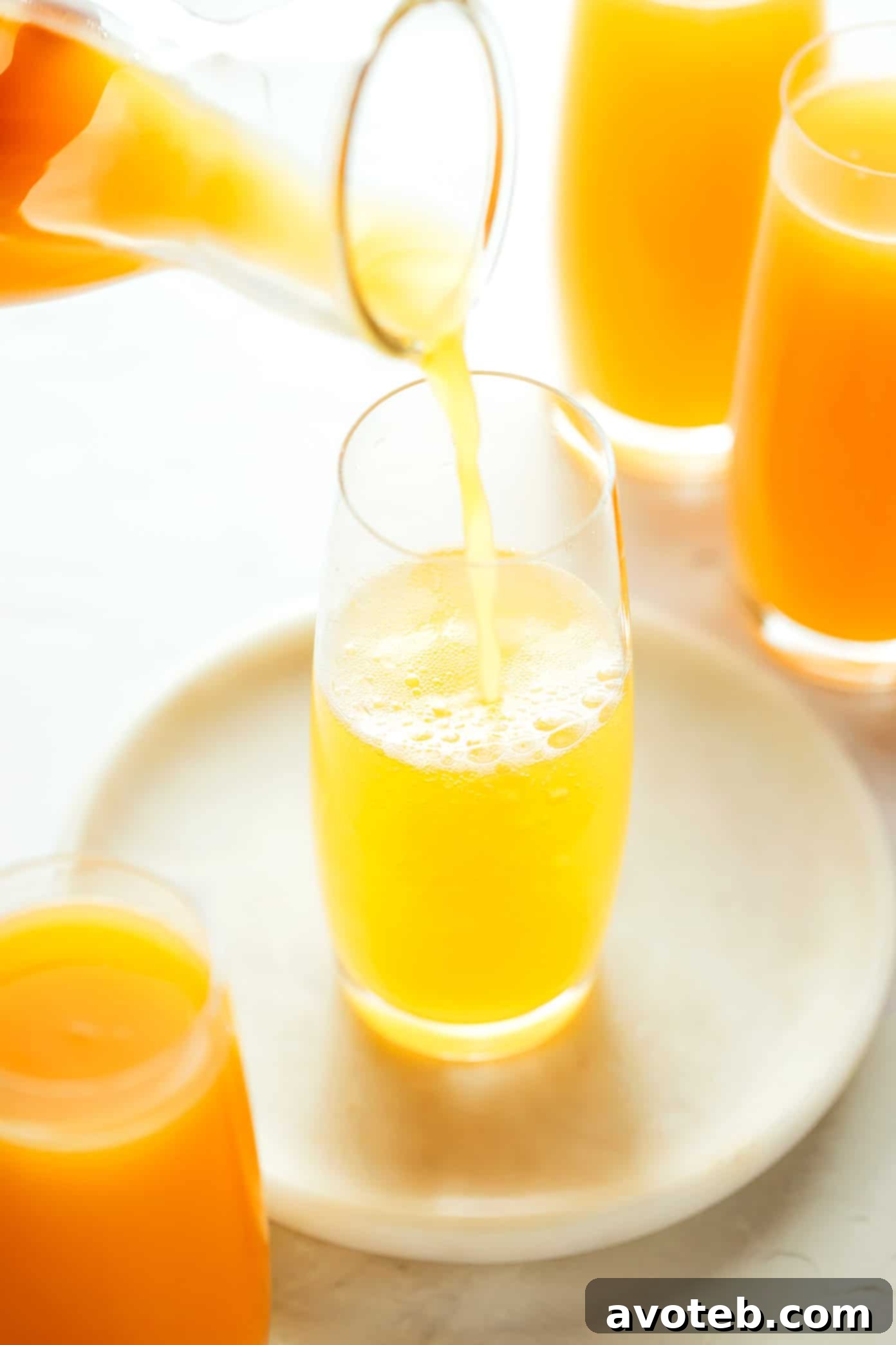 Mimosa Sunshine 4 Hand pouring sparkling wine into a mimosa glass
