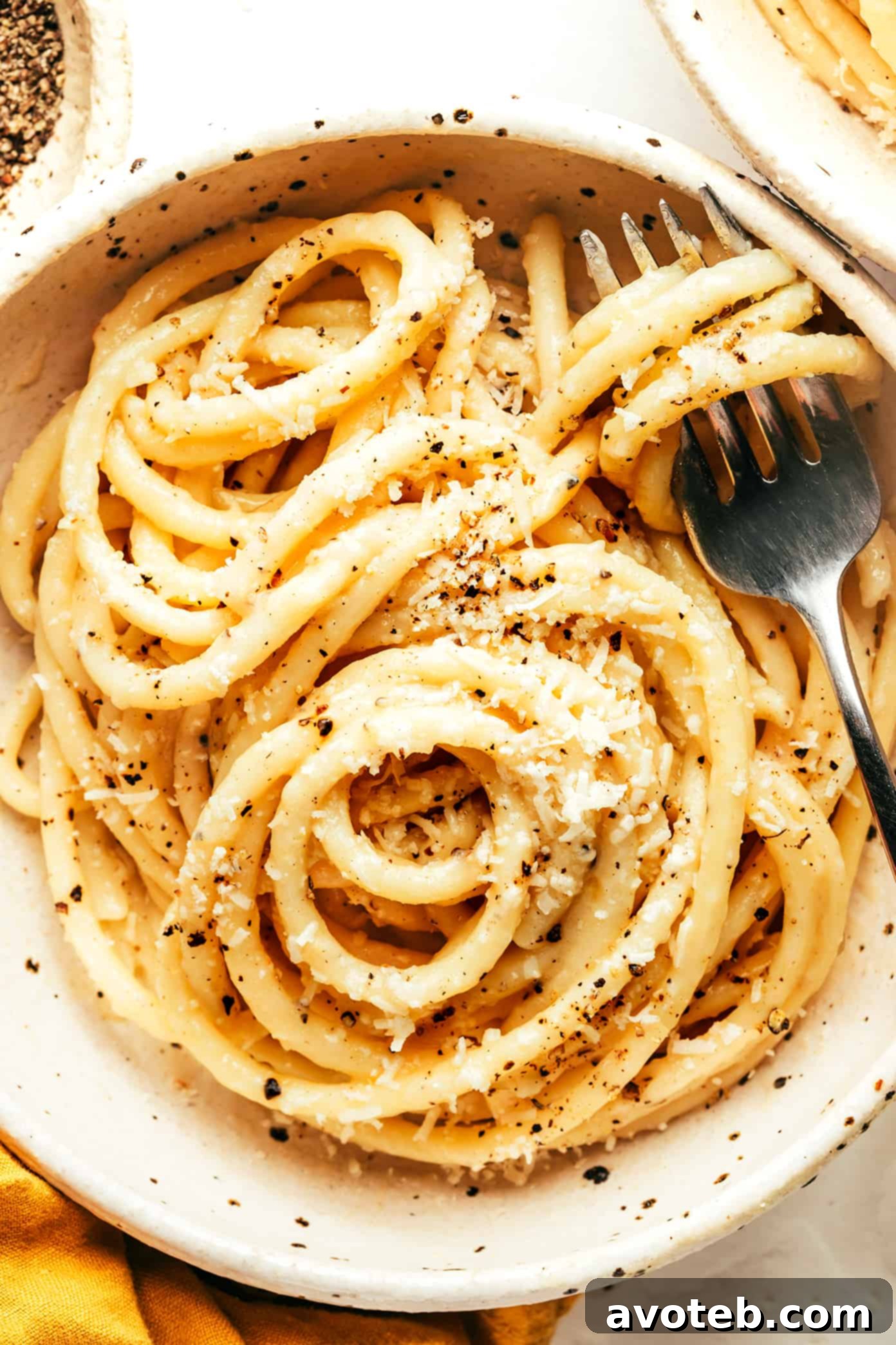 Close-up of the best Cacio e Pepe in a white bowl, showing the creamy, glossy sauce and perfectly coated bucatini pasta.