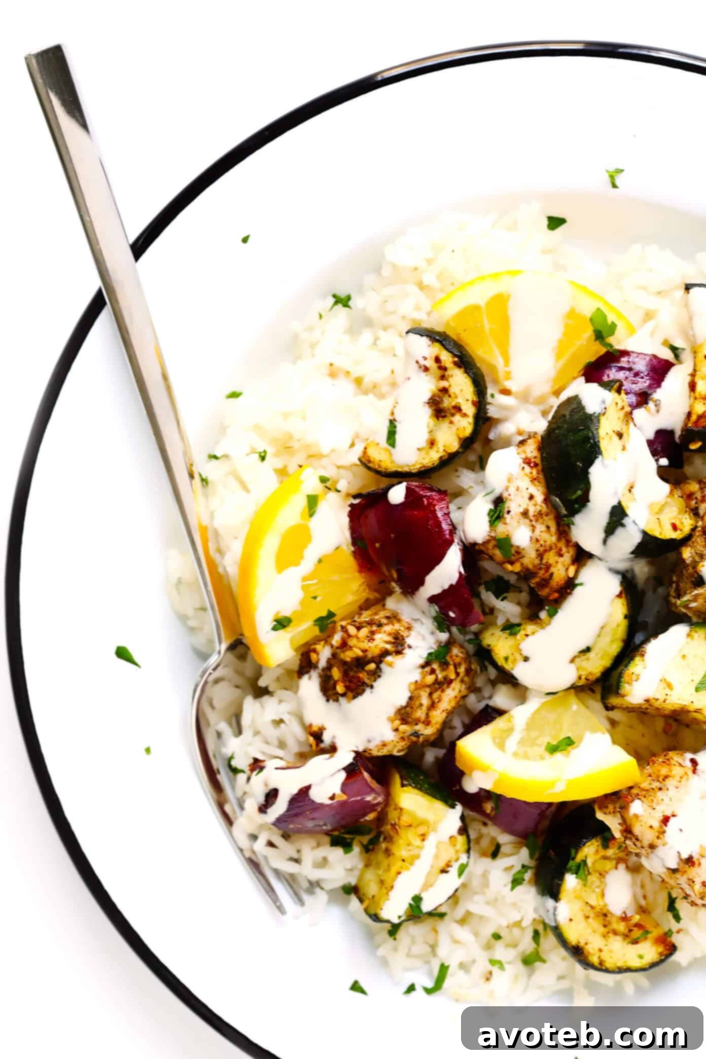 Za'atar Chicken and Vegetable Kabobs served over rice with a drizzle of tahini dressing.