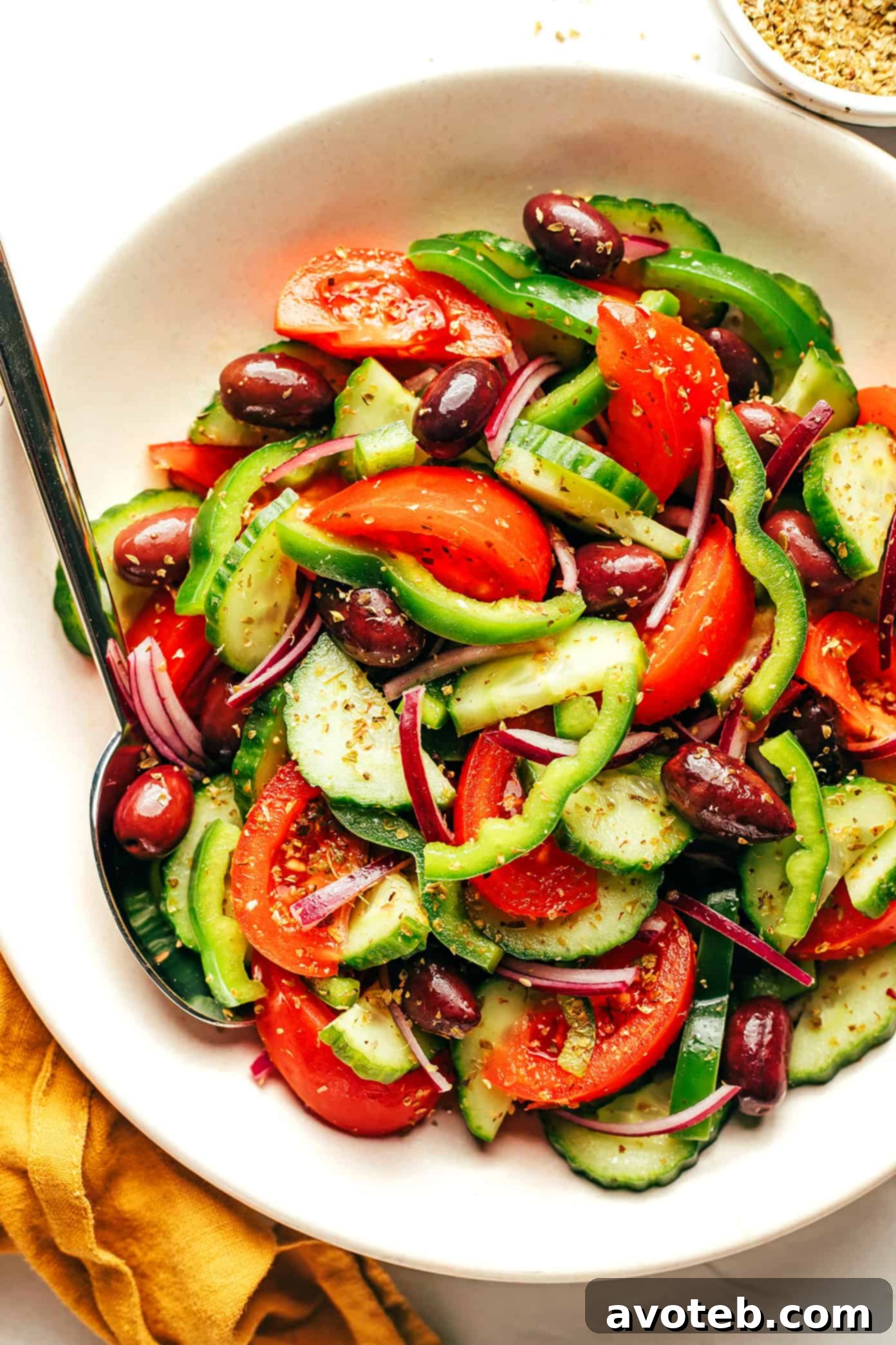 Authentic Greek Salad in a large bowl, surrounded by fresh ingredients
