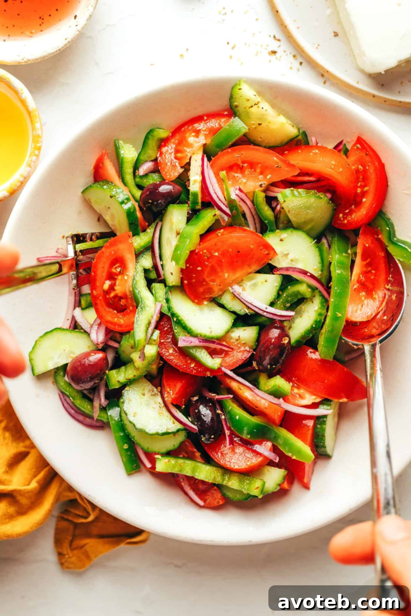 Hand drizzling olive oil over a prepared Greek salad