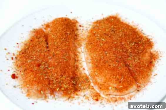 blackened tilapia seasoning being applied to fish fillets