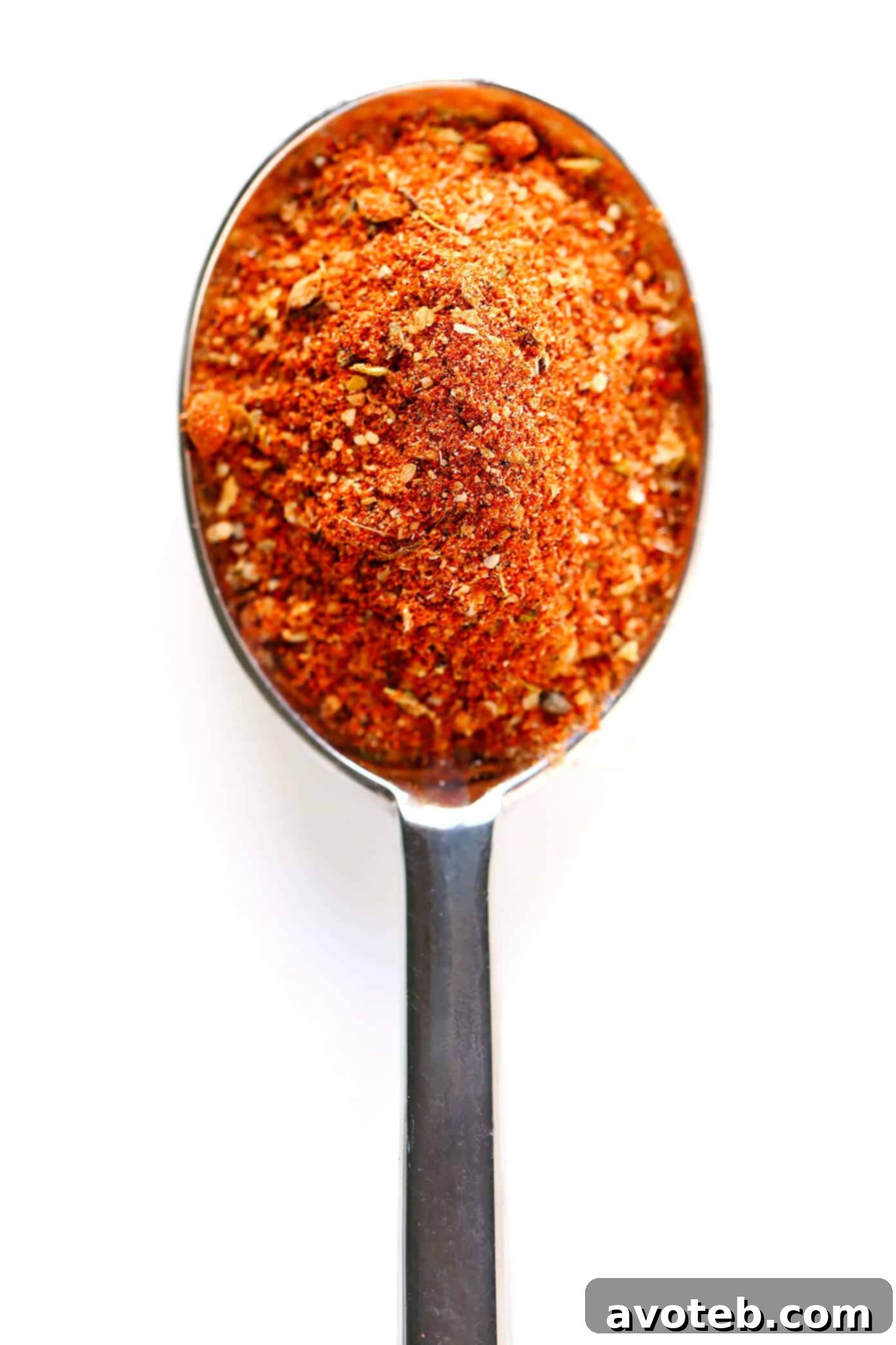 A close-up of various whole and ground spices laid out on a wooden surface, representing the ingredients for Cajun seasoning.