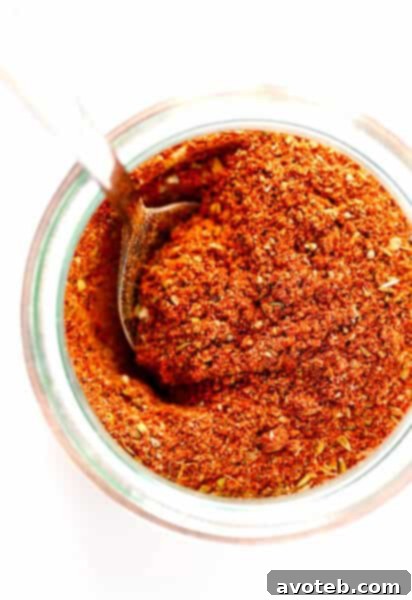 A final close-up shot of the homemade Cajun Seasoning in a small jar, with a spoon beside it, ready to be used.