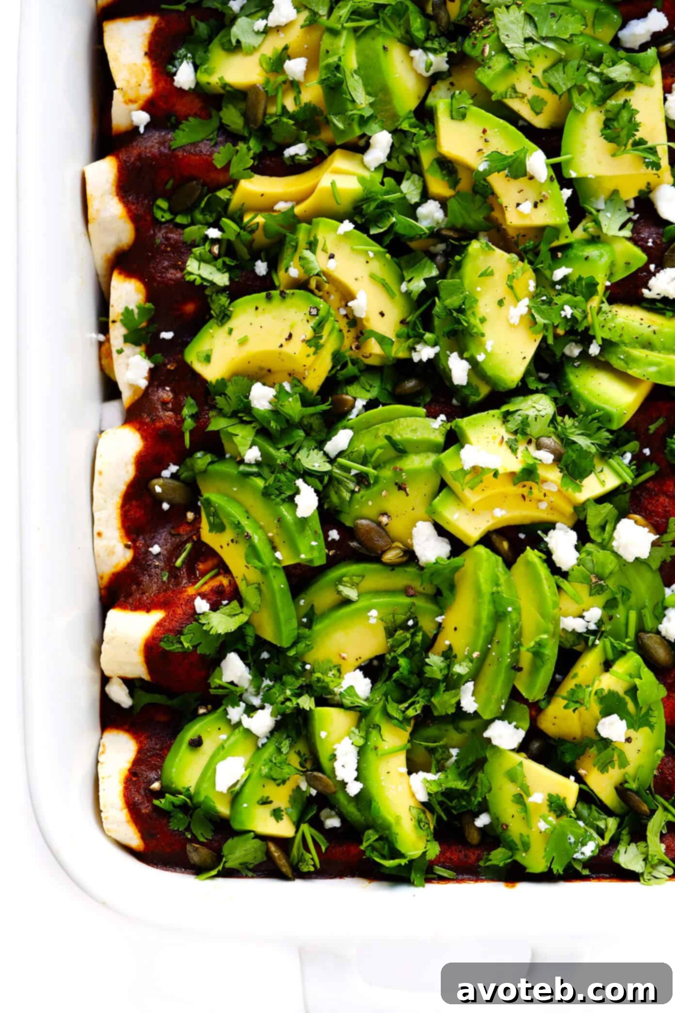 Delicious Roasted Cauliflower Enchiladas with creamy avocado slices, fresh cilantro, and a rich red sauce, perfect for a hearty vegetarian meal.