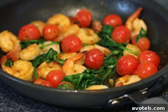 Sauteed Shrimp with Spinach & Tomatoes presented in a rustic style with fresh garnishes.