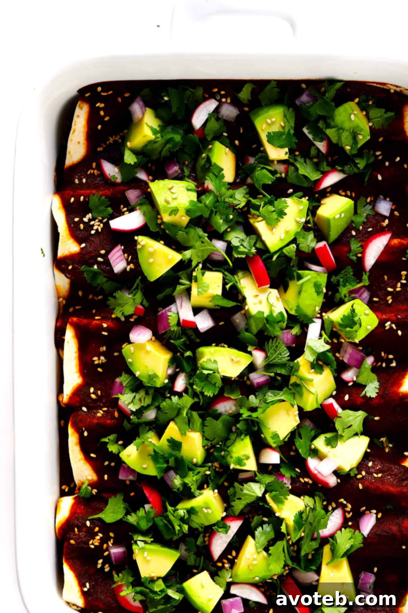 Plated Holy Mole Enchiladas with a side of avocado
