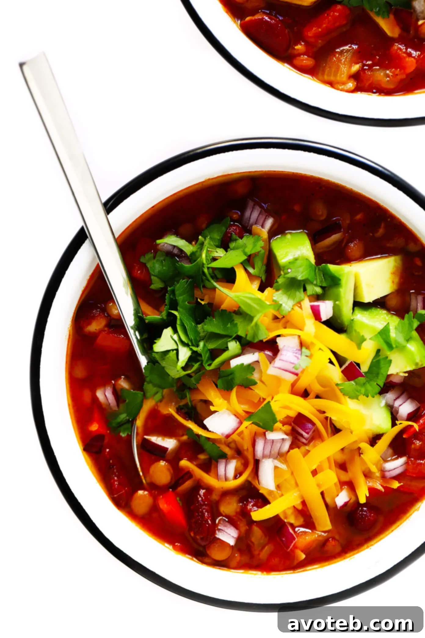 Hearty and flavorful vegetarian chili served in a rustic bowl, garnished with fresh cilantro and creamy avocado slices, ready to be enjoyed.