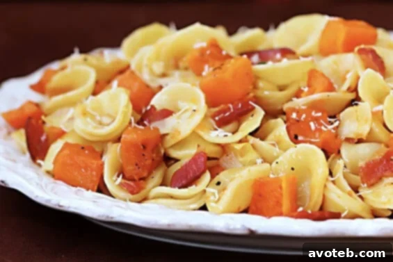 A vibrant bowl of Roasted Butternut & Bacon Pasta, showcasing golden butternut squash cubes, crispy bacon, fresh sage, and pasta, perfect for autumn.
