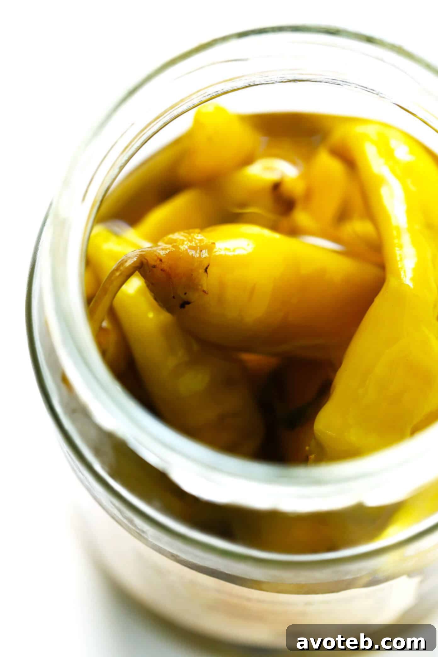 Close-up of vibrant yellow-green pepperoncini peppers in a jar, highlighting their appealing color