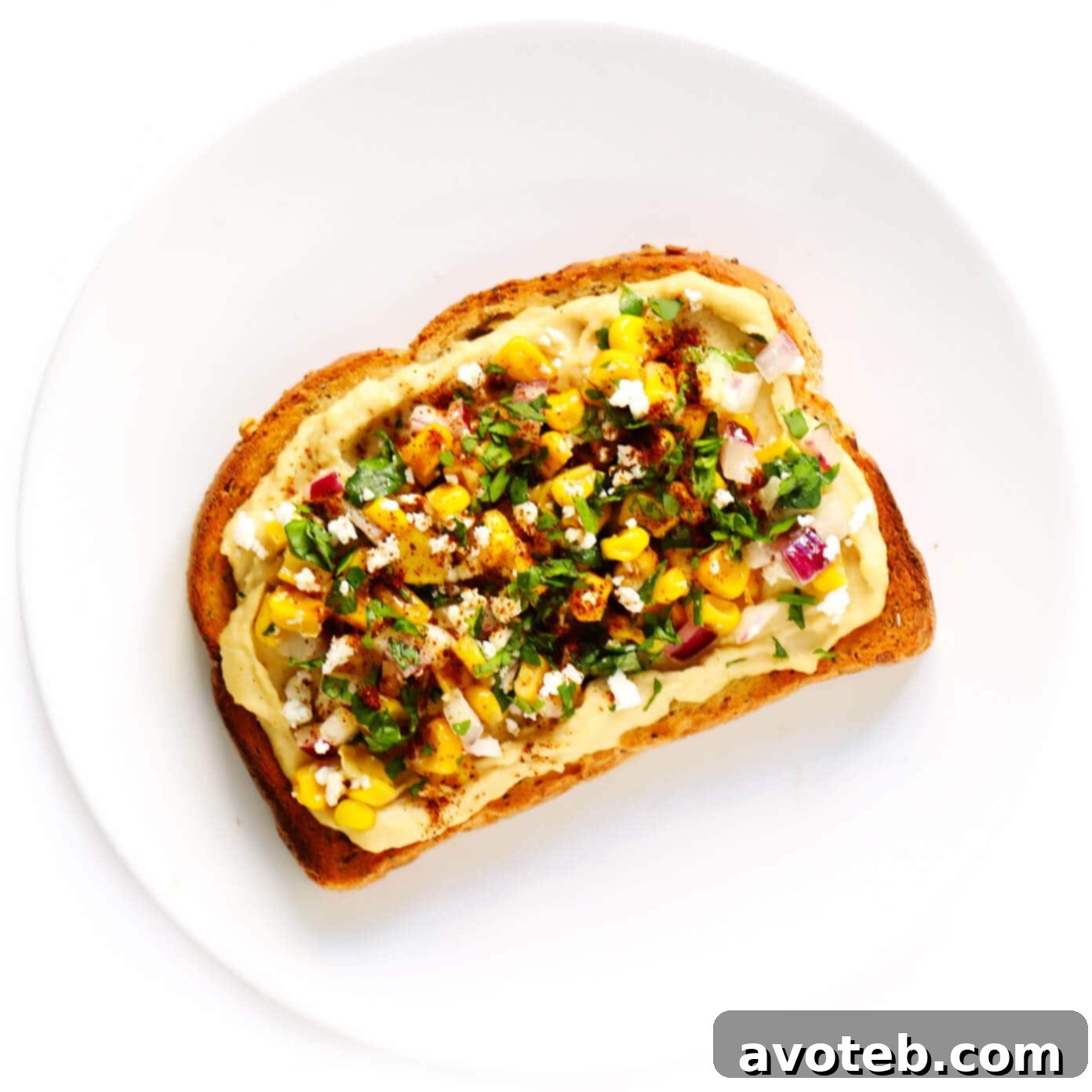 Hummus Toast with vibrant Elote (Mexican Street Corn) topping, featuring roasted corn and fresh herbs.