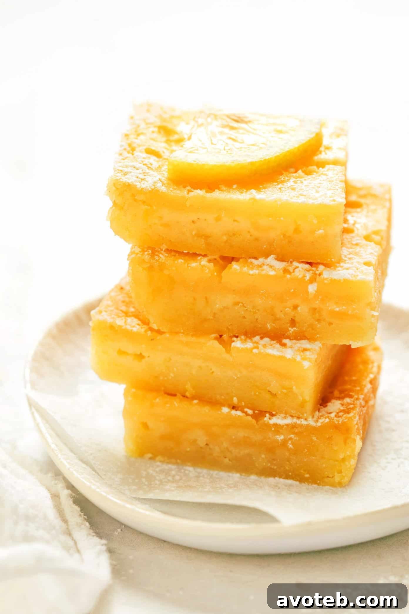 Simply Zesty Lemon Bars 6 Stack of five lemon bars with powdered sugar and lemon slices