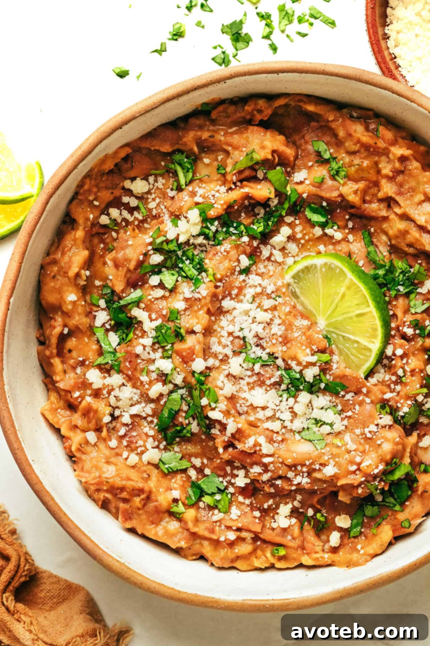 A close-up shot of creamy, homemade refried beans in a rustic bowl, garnished with fresh cilantro, ready to be served.