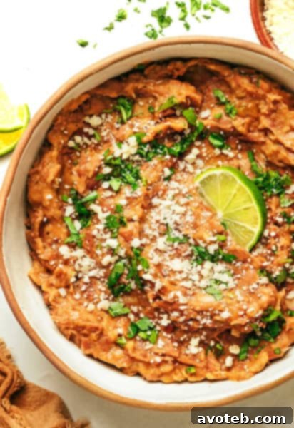 Creamy homemade refried beans garnished with fresh cilantro in a white bowl.