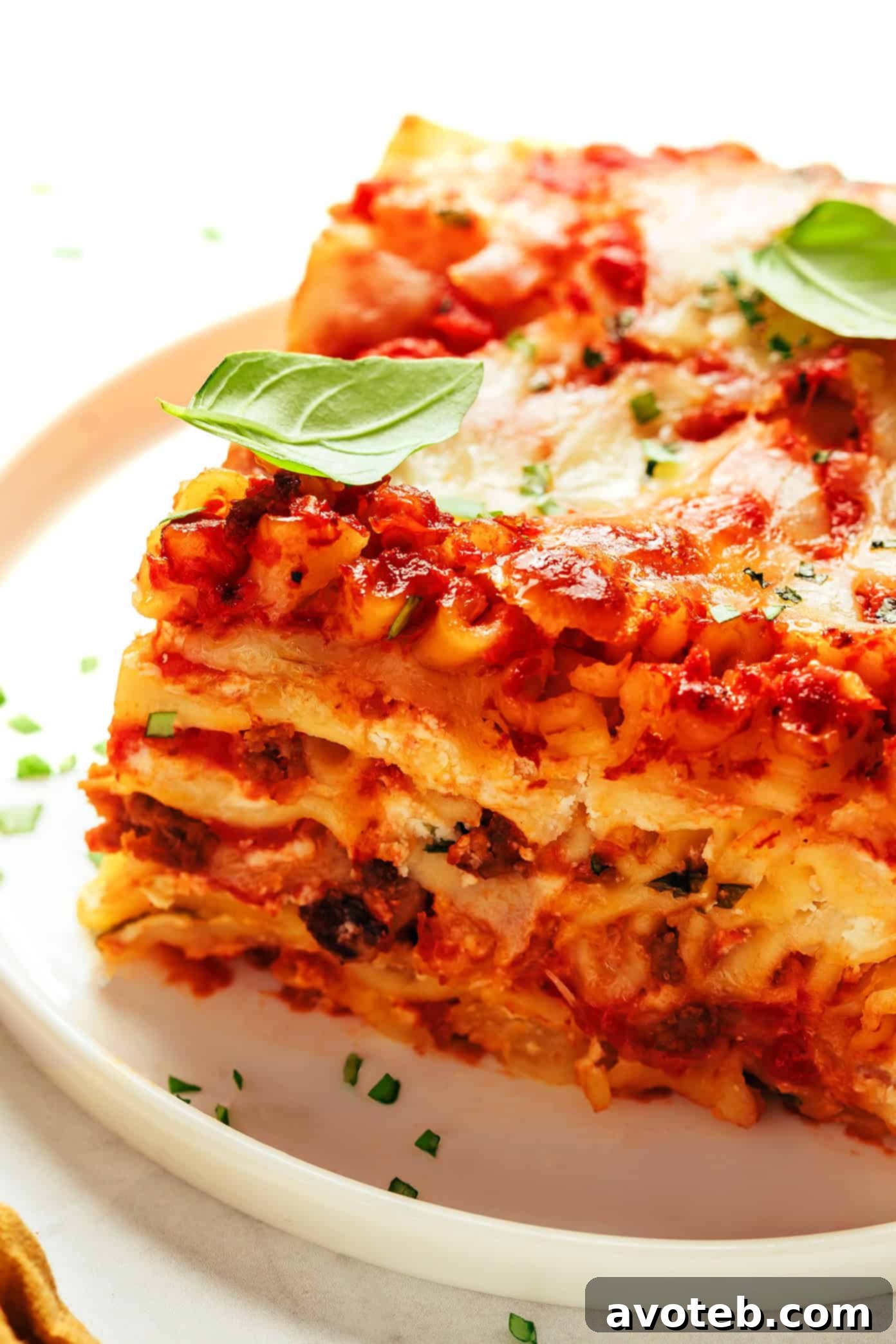 A delicious slice of classic lasagna on a white plate with a fork, ready to be eaten, showing the distinct layers.