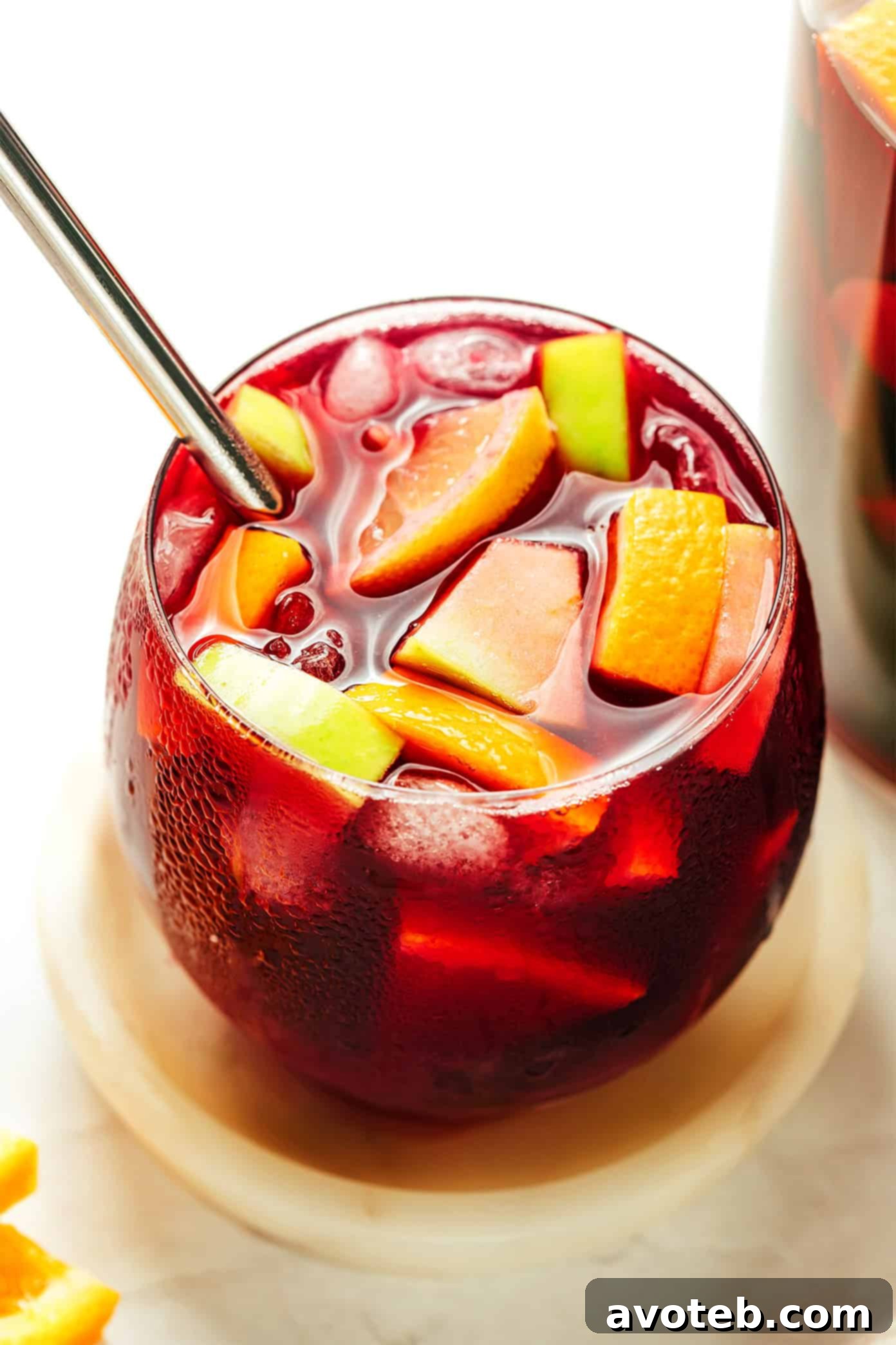 A pitcher of sangria being poured into a glass filled with ice and fruit, creating a refreshing summer drink.