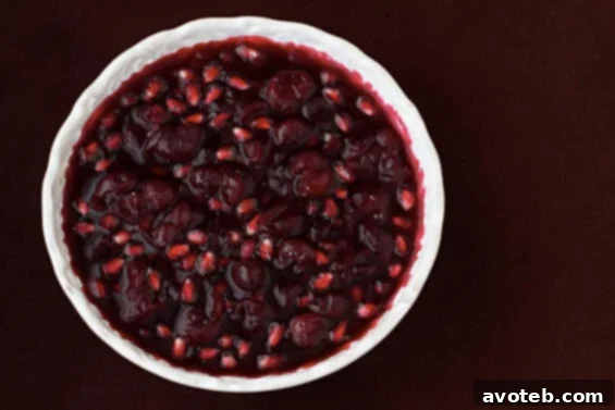 Cranberry-Pomegranate Sauce: A Festive Thanksgiving Side A vibrant bowl of homemade Cranberry-Pomegranate Sauce, garnished with fresh pomegranate seeds and cranberries, ready for Thanksgiving dinner.