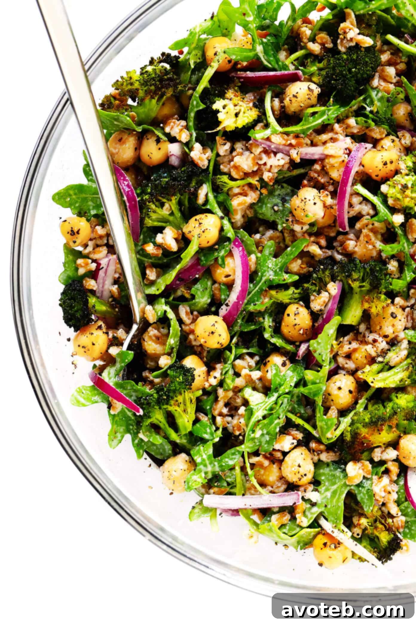 A beautifully assembled Roasted Broccoli and Farro Salad with chickpeas, arugula, avocado, and almonds in a large serving bowl.