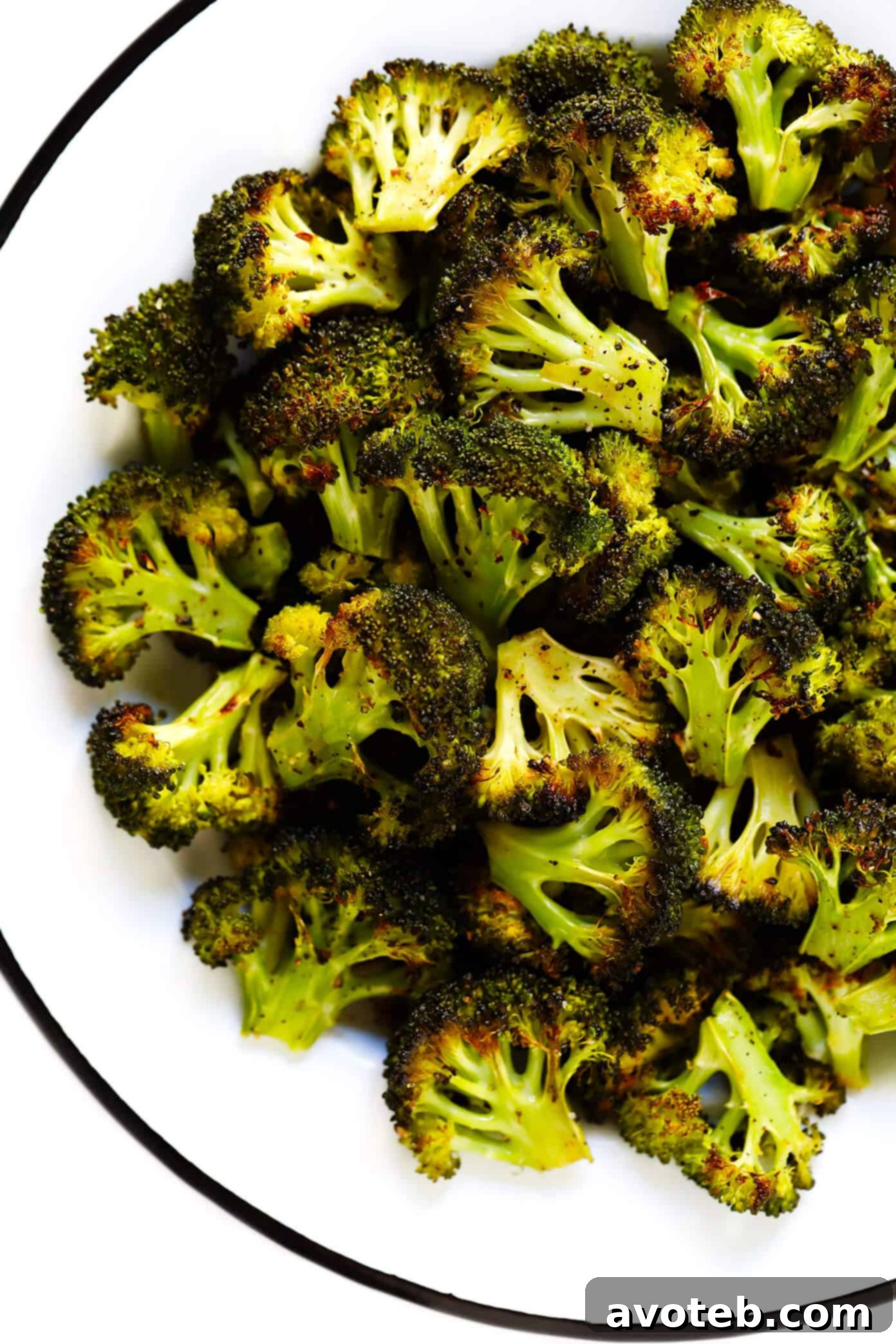 A serving of roasted broccoli with lemon wedges and fresh herbs, presented in a bowl, highlighting its vibrant green color and crispy texture.