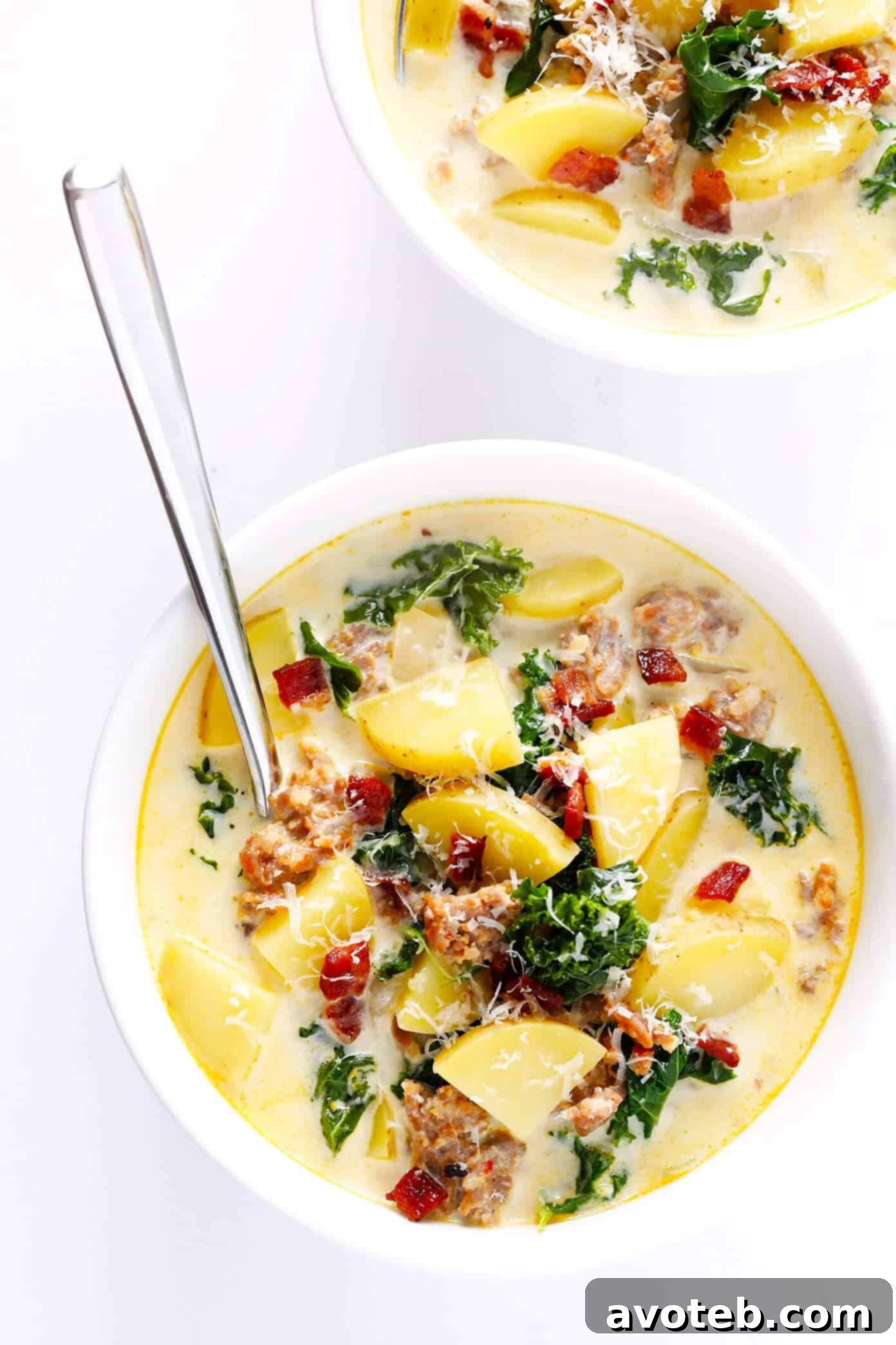 A close-up of a ladle dipping into a pot of Zuppa Toscana, showcasing the creamy, hearty soup with visible pieces of sausage, potatoes, and kale. The steam rises gently, emphasizing its warmth and inviting texture.
