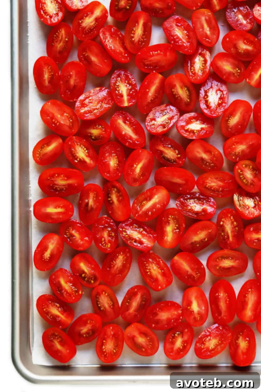 Learn how to make sun-dried tomatoes in the oven! This recipe can be easily customized to be as spicy, garlicky, herby or plain as you prefer. | gimmesomeoven.com #sundriedtomatoes #tomatoes #summer #topping #italian #healthy #vegan #glutenfree Roasted Tomatoes: Half-sliced tomatoes arranged on a parchment-lined baking sheet, seasoned with sea salt.