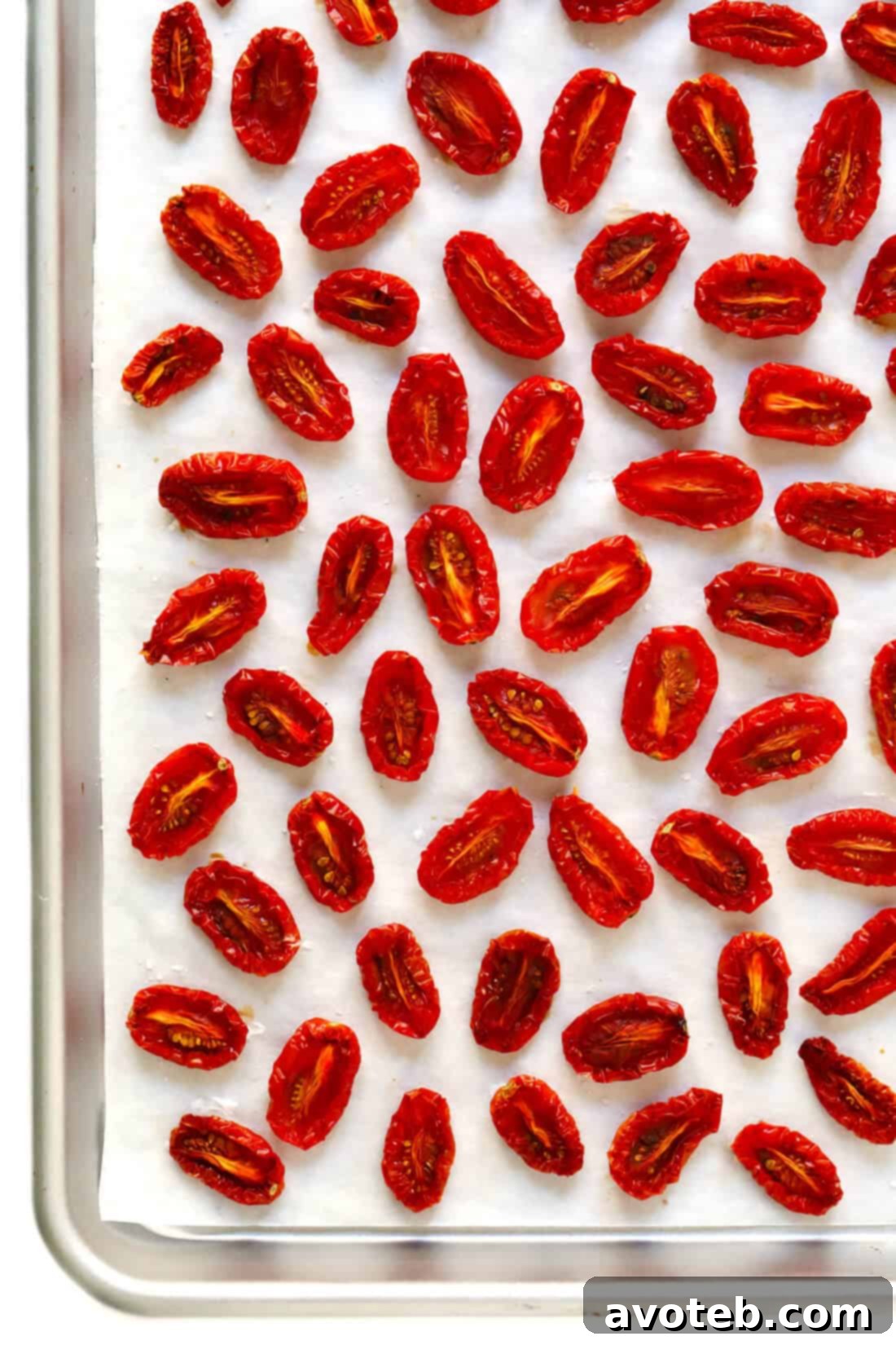 Learn how to make sun-dried tomatoes in the oven! This recipe can be easily customized to be as spicy, garlicky, herby or plain as you prefer. | gimmesomeoven.com #sundriedtomatoes #tomatoes #summer #topping #italian #healthy #vegan #glutenfree Oven-Dried Tomatoes: Close-up of perfectly dried tomato halves, shrunken and deeply colored, on a baking sheet.