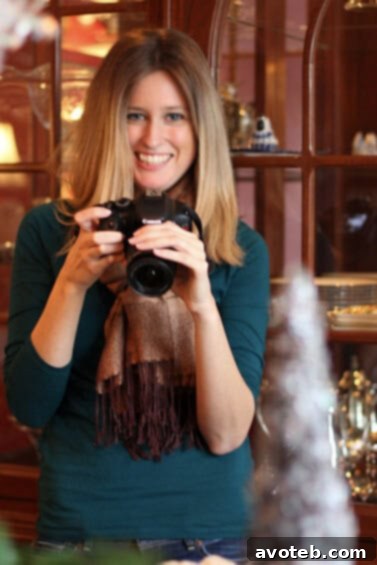 Megan, a Kansas City food blogger, smiling warmly at the cookie exchange event, holding a delightful dessert.