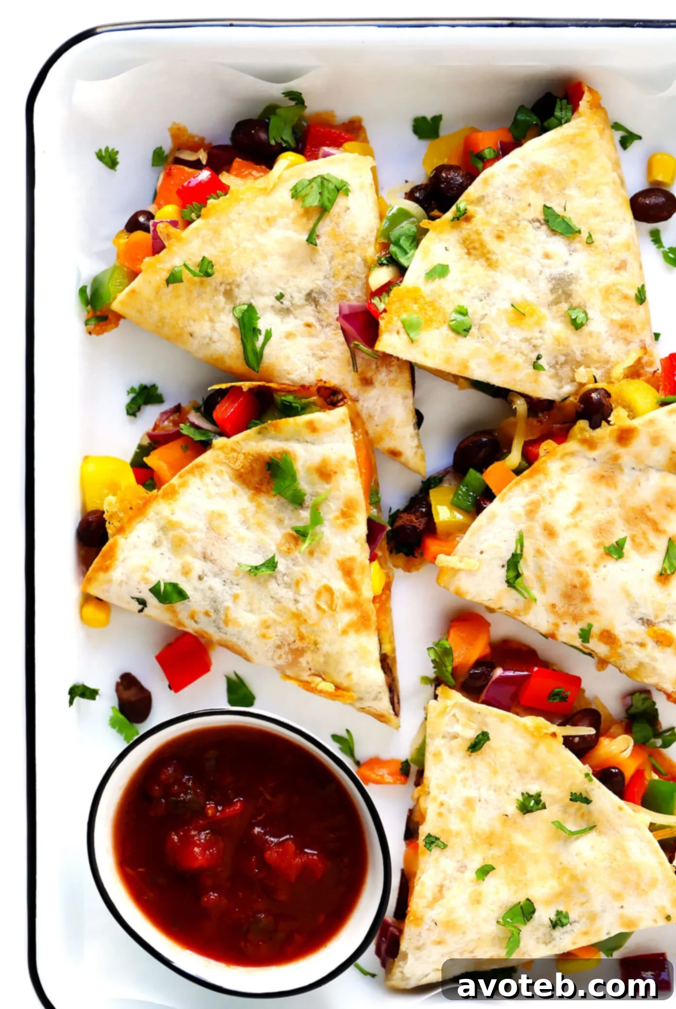 This easy veggie quesadilla recipe is 100% customizable with whatever veggies you have on hand. Feel free to add in an extra protein (such as chicken, beef or shrimp) if you'd like, and use whatever kind of tortillas and cheese you prefer. | gimmesomeoven.com #quesadilla #vegetarian #veggie #dinner #healthy #mexican #mealprep #freezermeal Hands holding a slice of veggie quesadilla with dipping sauce