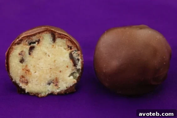 Decadent Chocolate Chip Cookie Dough Truffle A close-up of a perfectly dipped chocolate chip cookie dough truffle, showcasing its smooth chocolate coating and a hint of the cookie dough filling, ready to be enjoyed.