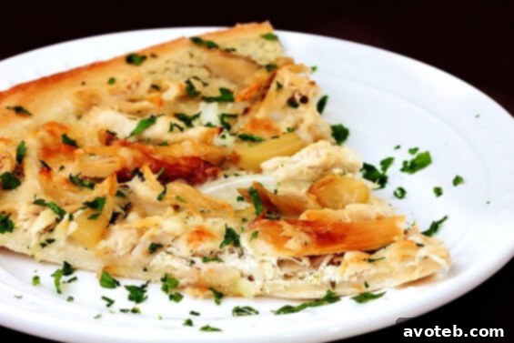 Close-up of a slice of Roasted Garlic Chicken Pizza, showcasing creamy base and melted cheese
