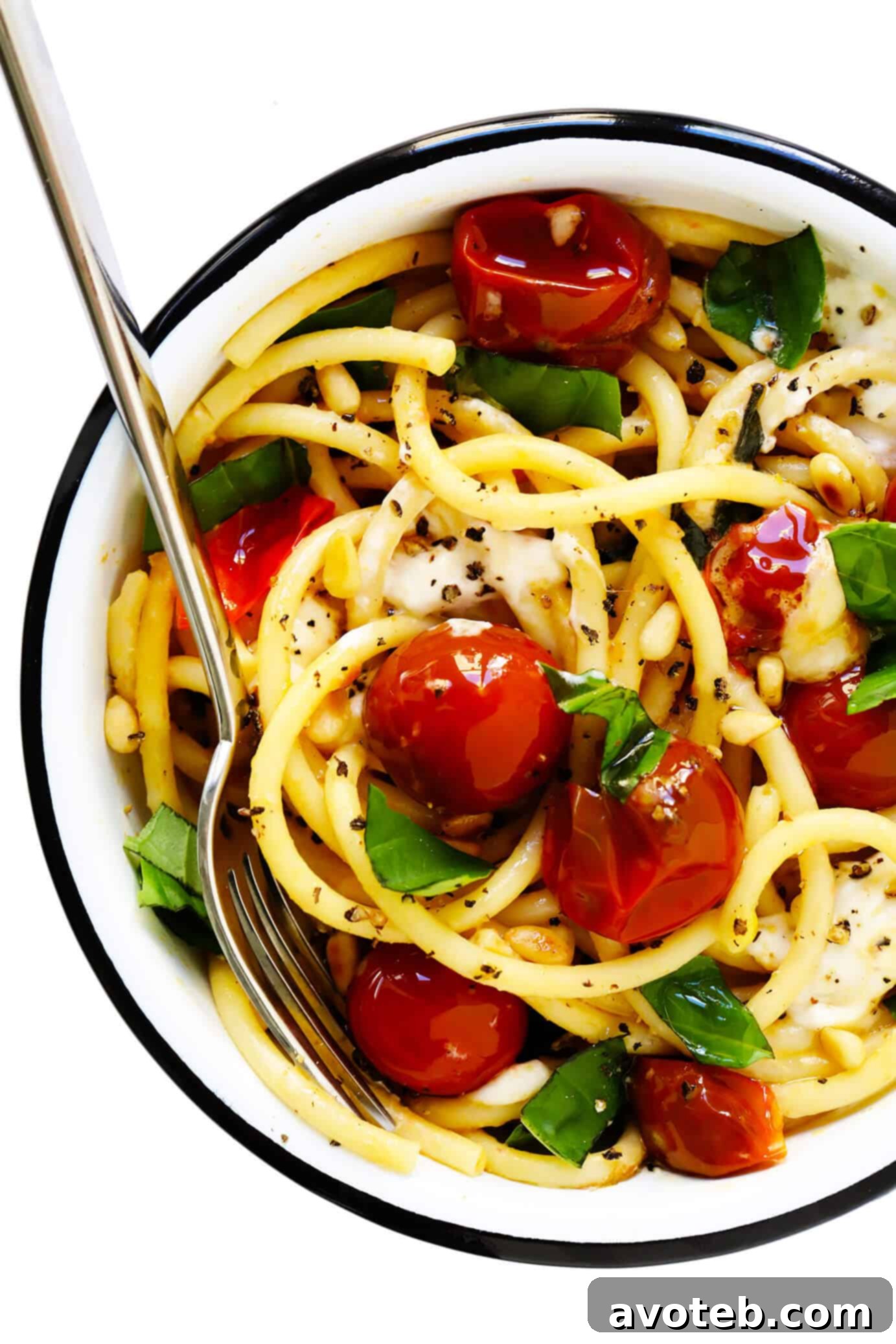 A beautifully plated serving of pasta featuring bright red burst cherry tomatoes, a generous dollop of creamy burrata, and fresh green basil, ready to be enjoyed.
