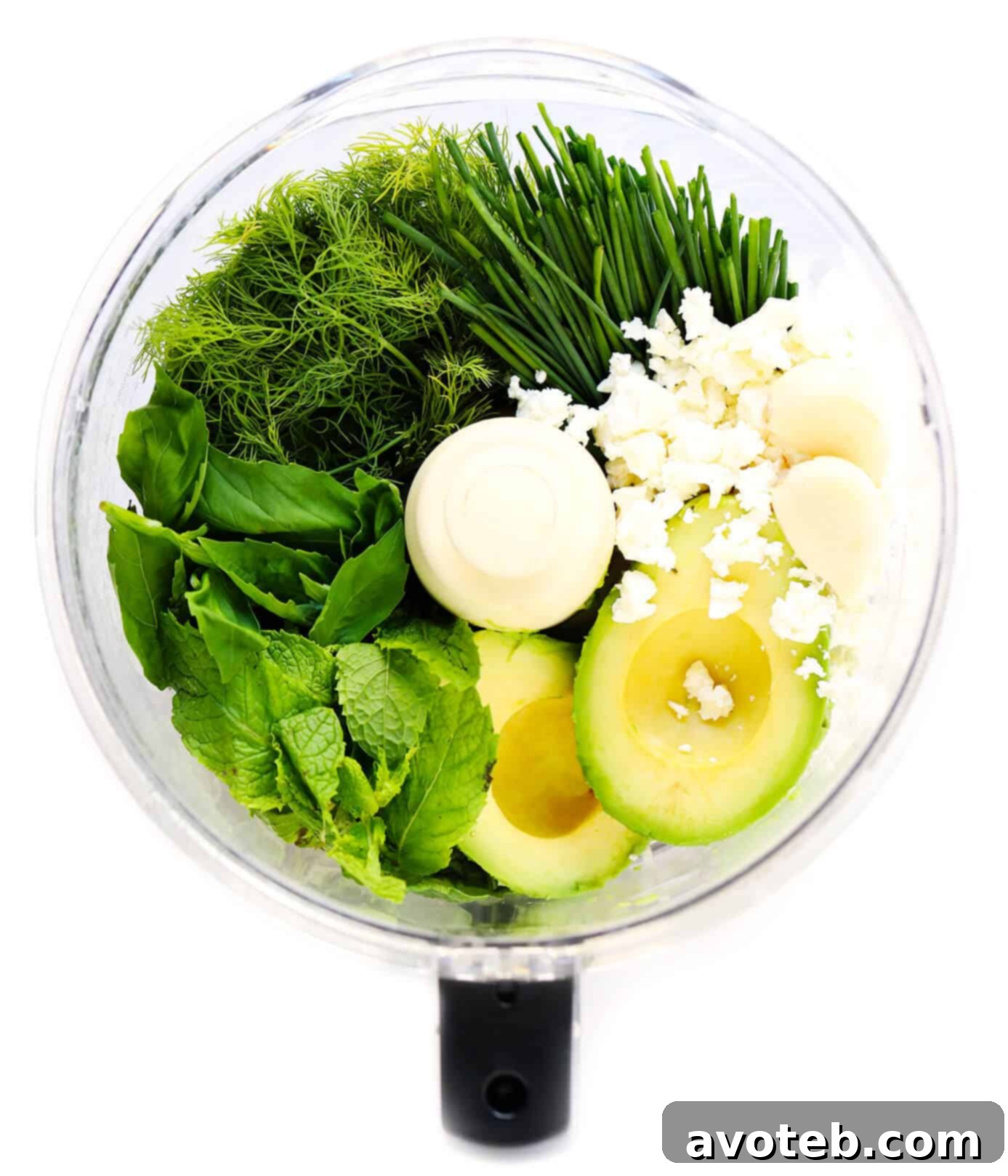 Array of fresh ingredients laid out: feta cheese, garlic, avocado, lemon, various herbs like dill, mint, basil, and chives, alongside Dijon mustard and olive oil.