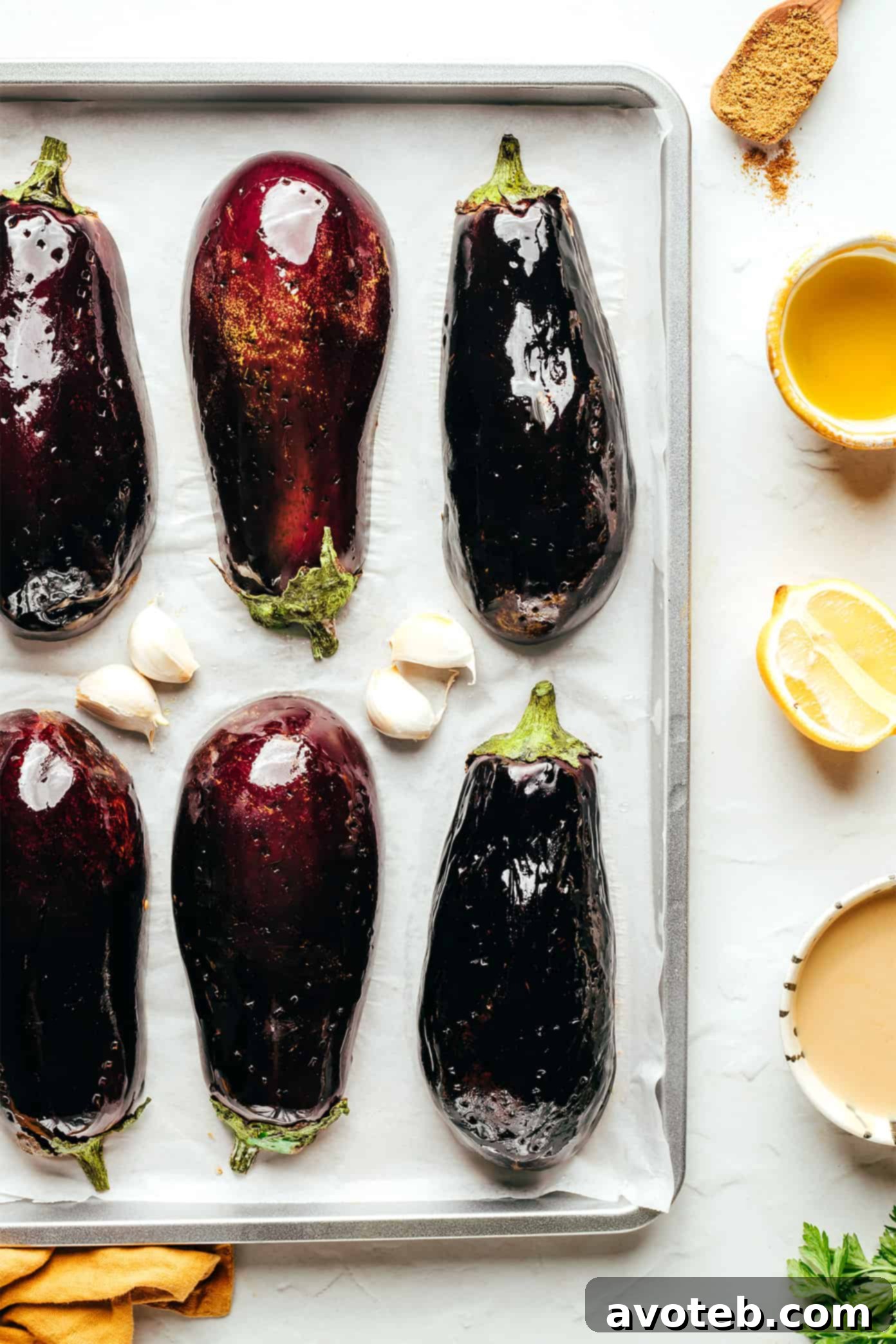 Ingredients for Baba Ganoush laid out on a table, including roasted eggplant, tahini, lemon, garlic, and herbs.