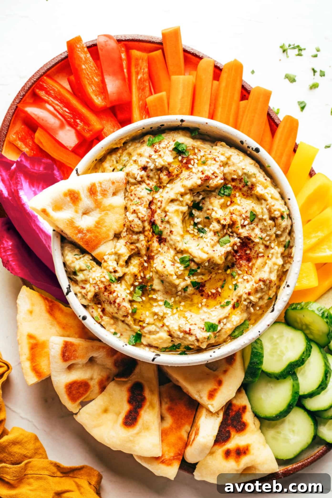 A vibrant table setting featuring a variety of Mediterranean dips and small plates, including Baba Ganoush, hummus, olives, and fresh vegetables.