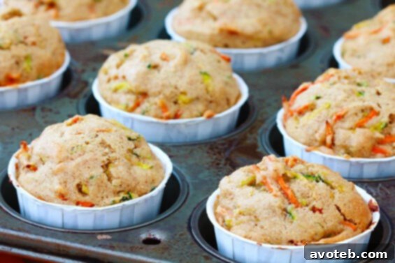 A tray of freshly baked carrot zucchini muffins cooling on a wire rack.
