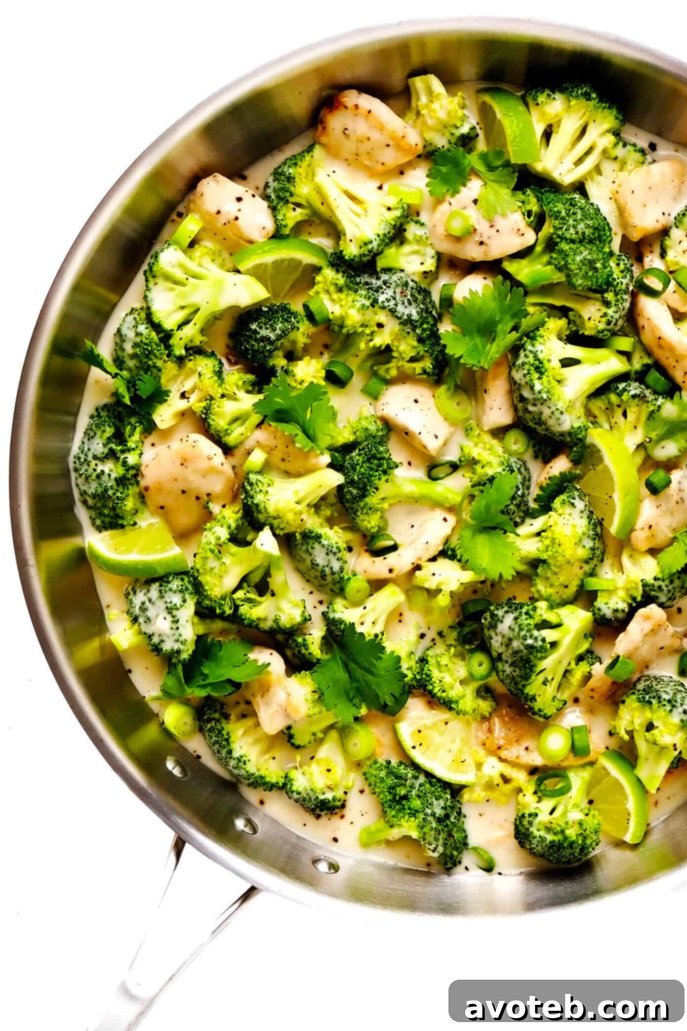 Close-up of chicken and broccoli coated in creamy coconut lime sauce in a pan