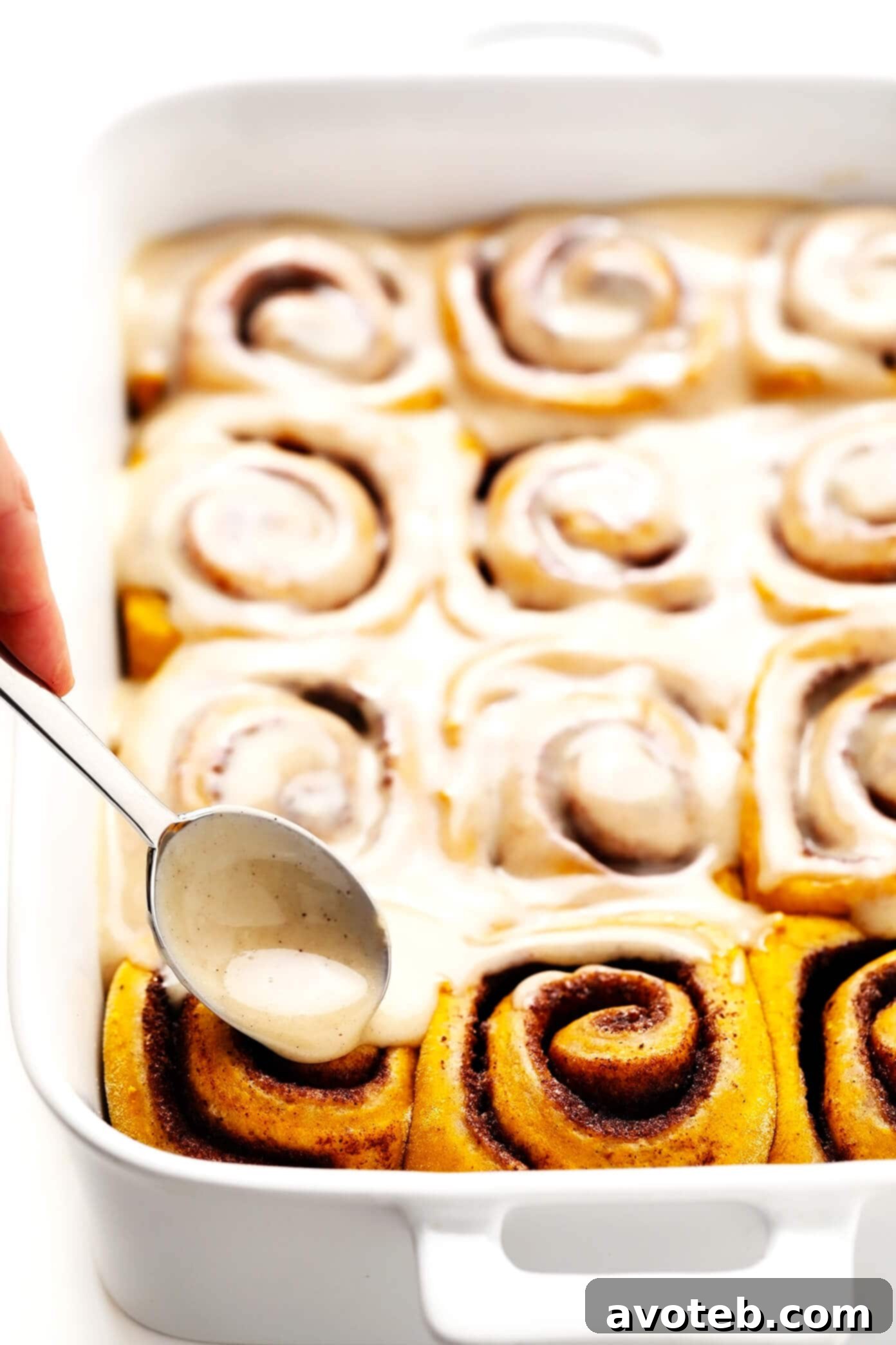 Irresistible Pumpkin Cinnamon Rolls with a generous drizzle of Maple Cream Cheese Frosting, perfect for a cozy fall breakfast or dessert.