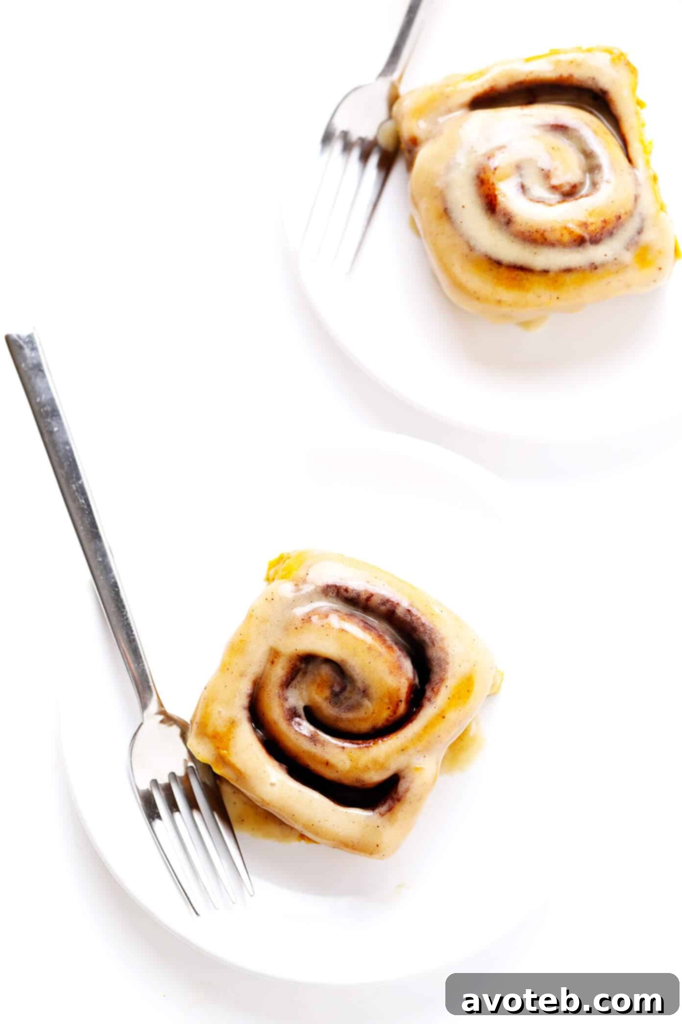 Individual pumpkin cinnamon rolls served beautifully on plates with forks, inviting a delicious breakfast, brunch, or dessert experience.